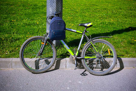 Bicycle with a backpack standing near a pillar on the asphalt on a background of grassの写真素材