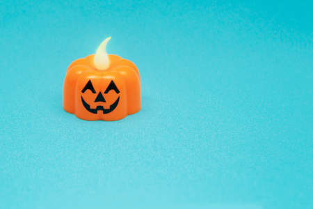 Smiling Halloween candle pumpkin on a blue background. Symbol of a kindly bright halloween. Plastic electric lamp.の写真素材