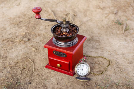 Retro coffee grinder with coffee beans and vintage bronze pocket watch, 9 oclock. Morning coffee...