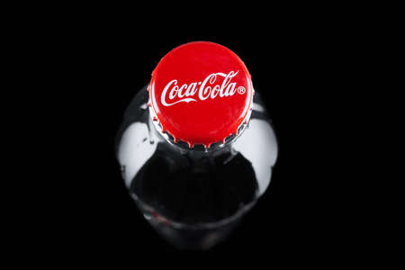 Glass bottle of coca cola with red cap, top view on black background - Russia, St. Petersburg, February 2021.のeditorial素材