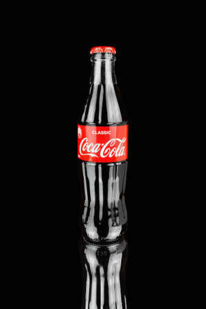 Glass bottle with Coca Cola with red cap and label on black mirrored surface - Russia, St. Petersburg, February 2021.のeditorial素材