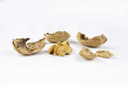 Broken walnut on white surface. Pieces of shell and half of core.