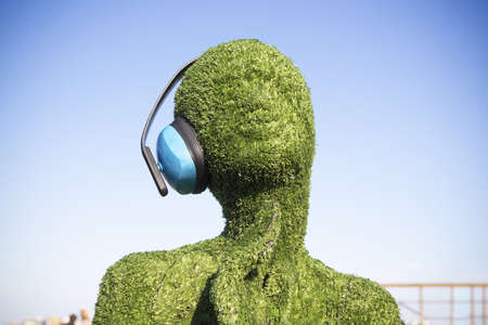 Female figure covered with artificial green grass with headphones against the blue sky - Loft project Floors Etagi, Saint Petersburg, Russia, April 2021のeditorial素材