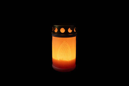 Burning candle in grave lamp in the dark.