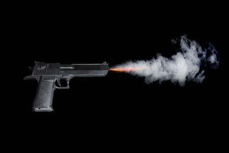 Black pistol shooting with fire and smoke on dark background.