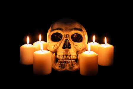 Human skull among burning candles in the dark, scary still life, altar.の写真素材