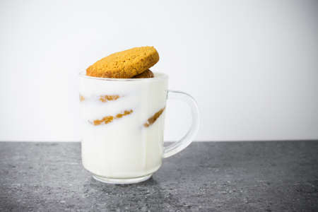 Stack of round cookies soaked in milk in a transparent glass cupの写真素材