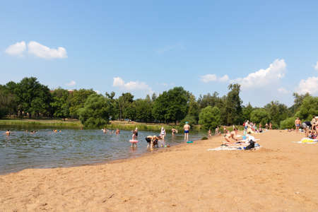 People resting on the beach among green trees and yellow sand - Russia, St. Petersburg, August 2021のeditorial素材