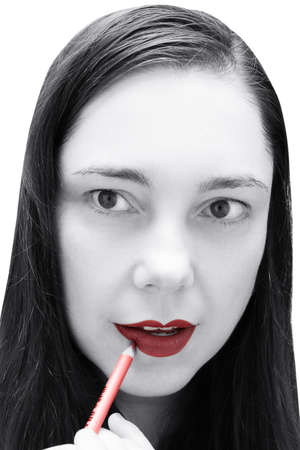 Woman's face with red lips and white skin, girl painting lips with red pencilの写真素材