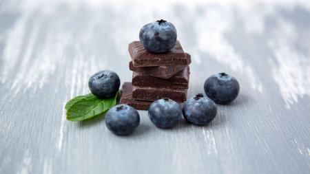Close up Dark Chocolate Stack Fresh Organic Blueberries Fresh Mint Leaves on Wooden Background Natural Light Selective Focusの写真素材