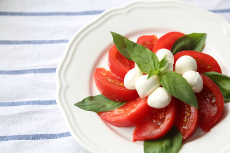 Tomato Mozzarella Cheese and Basil Leaf on White Plate Natural Light Selective Focusの写真素材