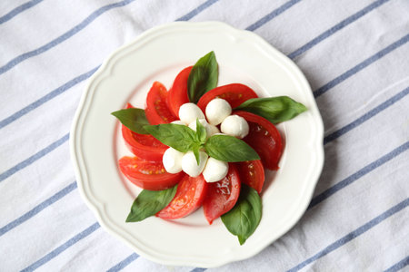Tomato Mozzarella Cheese and Basil Leaf on White Plate Natural Light Selective Focusの写真素材