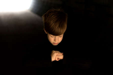 Boy praying in the dark, light at the end of the tunnelの写真素材