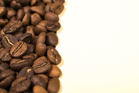 Scattered roasted coffee beans on beige backgroundの写真素材