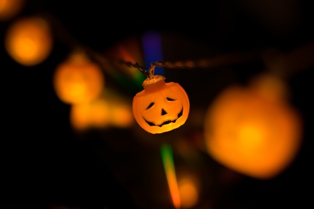 Halloween orange carved pumpkin garland glowing in the dark with brurred elements and . Mystical and spooky holiday concept.の写真素材
