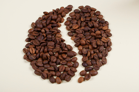Roasted brown coffee beans laid forming a shape of a big coffee bean.の写真素材