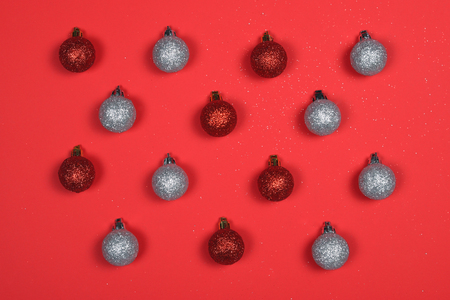 Pattern of glitter and shiny red and silver Christmas baubles on red background with sparkles.の写真素材