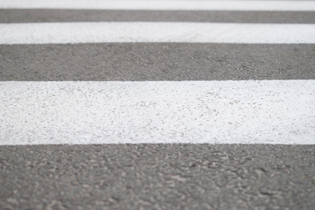 Part of asphalt road with crosswalk white marking lines, close-up. Background which can be used for text.の写真素材