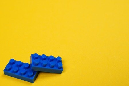 Two blue constructor blocks on yellow background with space for text.の写真素材