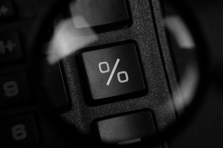 Top view of a percentage sign through magnetic glass on black background. Savings and economy concept.の写真素材