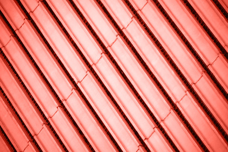 Parallel stripes of concrete facade wall diagonal pattern toned in Living Coral color of the year 2019.の写真素材