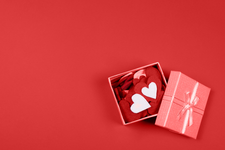 Valentines felt fiber hearts in a beautiful gift box on vibrant red background. Happy Women's, Mother's, and Valentine's Day and love concept. Top view with copy space.の写真素材