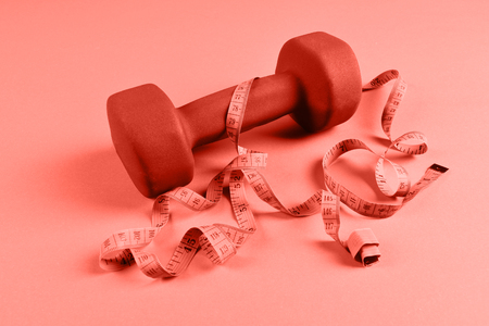 One blue dumbbell and measuring tape on orange backgroundの写真素材