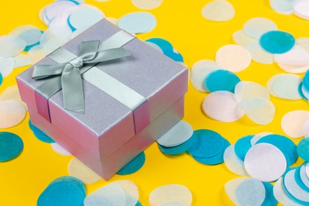 Present box on yellow background with multicolored confetti.の写真素材