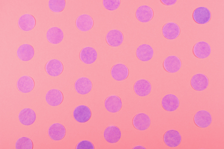 Trendy pink background decorated with purple pastel paper round confetti arranged as polka dot. Festive holiday backdrop with copy space.の写真素材