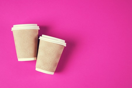 Two paper coffee cups on pink background.の写真素材