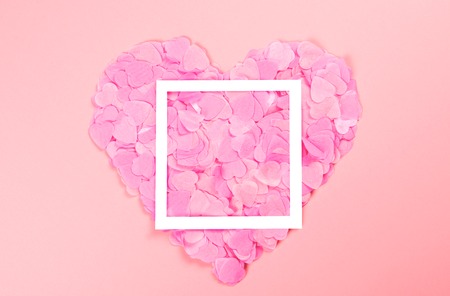 Elegant and tender pink heart of scattered heart-shaped confetti with white frame. The mood of...