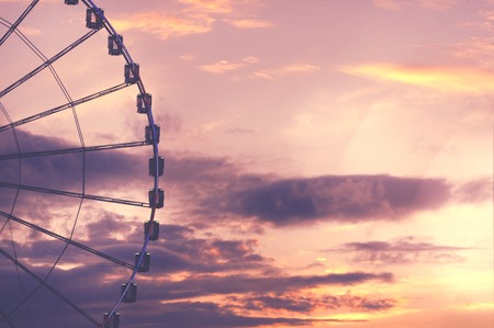 Ferris wheel against beautiful, dramatic sky with sun beams during the sunset. Bachground with copy space for text.の写真素材