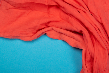 Texture of cotton fabric of vibrant coral color on blue background. Trendy beautiful creative backdrop. Fashion concept.の写真素材