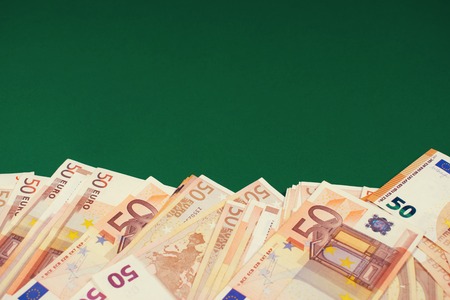 Fan of fifty euro banknotes on a green background with copy space for text. Budgeting, finance and...