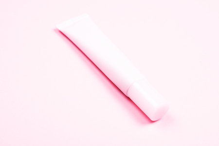 Pastel pink cosmetic tube on the background of the same tone. Body care and beauty concept.の写真素材