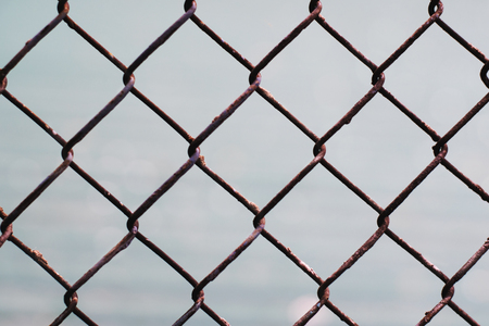 Chain-link old rusty fencing seamless pattern on grey background, metal wire mesh fence.の写真素材