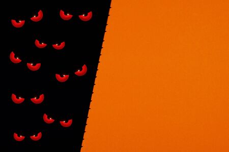 Serious and evil spirit eyes looking in the dark on black and orange background with copy space as a...