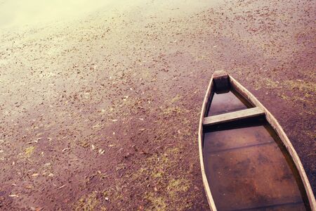 Old wooden boat in a river dirty water.