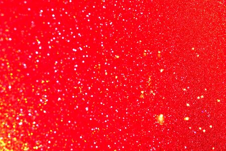 Shiny red and golden defocused glitter background with copy space. Creative holiday and festive backdrop.の写真素材