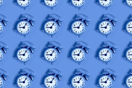 Pattern of analogue classic alarm clock showing eight in the morning on blue background. Flat lay...