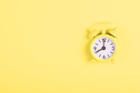 Alarm clock on yellow background.