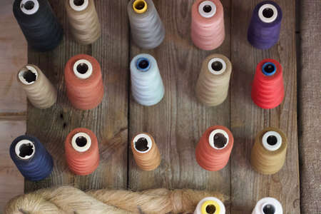 Colorful thread spools on wooden background, top view. Tailoring concept