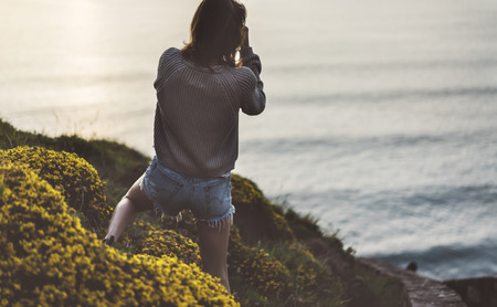 Clouds sky and sunlight sunset on horizon ocean. Silhouette person tourist traveler photographer making pictures seascape on vintage photo camera on background sunrise. Relax view, mockup evening natureの写真素材