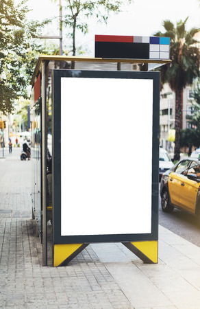 Blank advertising light box on bus stop, mockup of empty ad billboard on night bus station, template banner on background city street for message or text in Barcelona, afisha board and headlights of taxi carsの写真素材