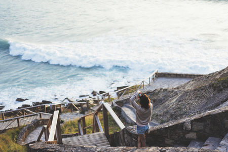 Clouds sky and sunlight sunset on horizon ocean. Silhouette person tourist traveler photographer making pictures seascape on vintage photo camera on background sunrise. Relax view, mockup evening natureの写真素材