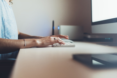 Businesswomen working at office with monitor computer, young hipster manager typing on keyboard, closeup finger female hands texting message, work process concept in workspace, night atmospheric 
の写真素材