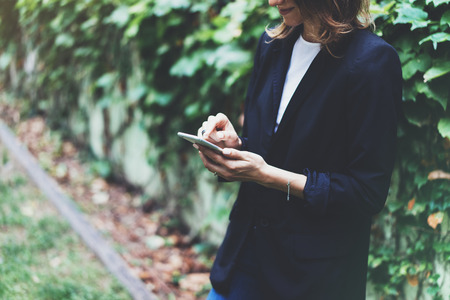 Portrait young businesswomen in black suit using smartphone isolated on background green nature wall mockup, pretty hipster manager holding mobile gadget, girl smile and texting message, connectの写真素材