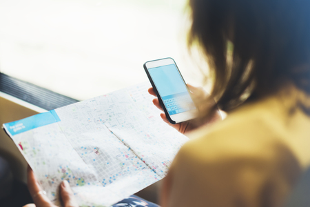 Enjoying travel. Young pretty woman traveling by train sitting near the window using smartphone and looking map. Tourist texting online message and plan route of railway, railroad transport conceptの写真素材