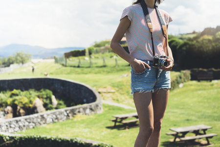 Tourist traveler photographer making pictures sea scape on vintage photo camera on background ocean, hipster girl enjoying green peak mountain and nature holiday, mock up waves view, blurred backdropの写真素材