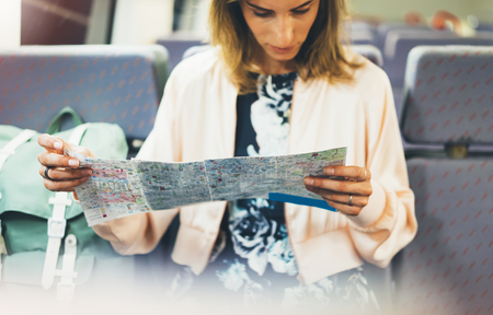 Enjoying travel. Young hipster smile girl with backpack traveling by train sitting near the window...